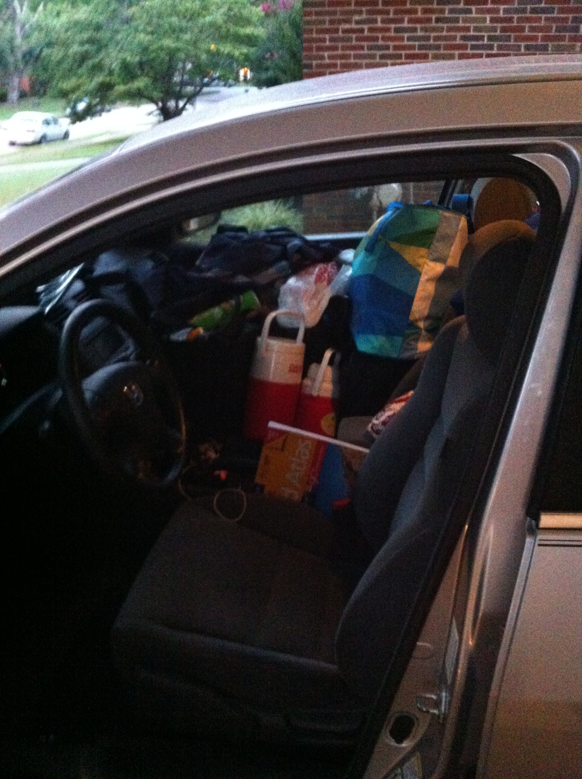 Front passenger seat of car piled high with tote bags and suitcases.