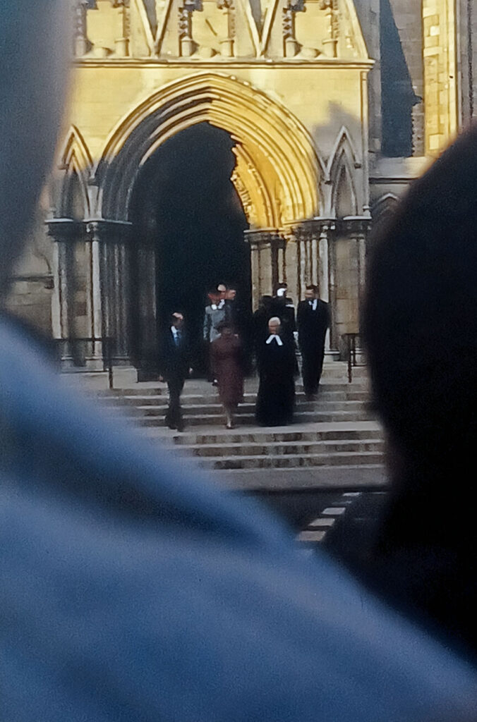 Queen Elizabeth II descends the south transept steps at York Minster. She is flanked by the Duke of Edinburgh and the Archbishop of York. This happened on November 4, 1988.