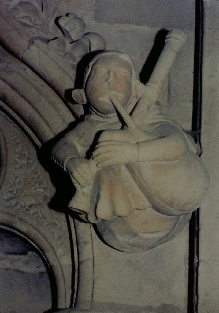 Medieval carving of a minstrel playing the bagpipes. The carving is on the north wall of the nave of Beverley Minster.